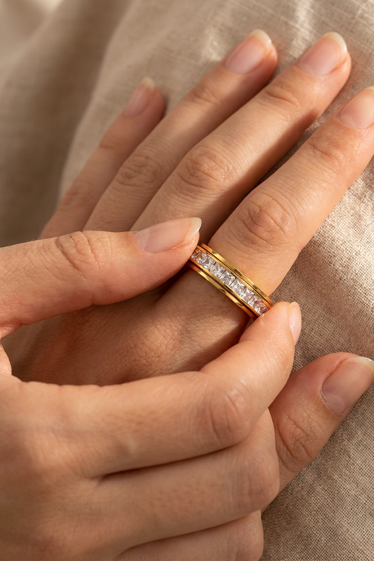 Gold Calma spinner ring worn on a hand