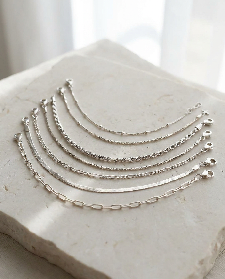 Sei six dainty silver chain bracelets on limestone
