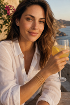Woman on a terrace wearing the Sei gold bracelet stack