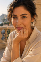 Woman resting her chin on her hand wearing the Atrani Orbit Ring on a stone terrace
