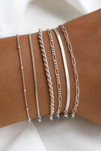 All six dainty silver chains stacked on a wrist