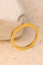 Basta Band gold engraved ring resting on travertine stone