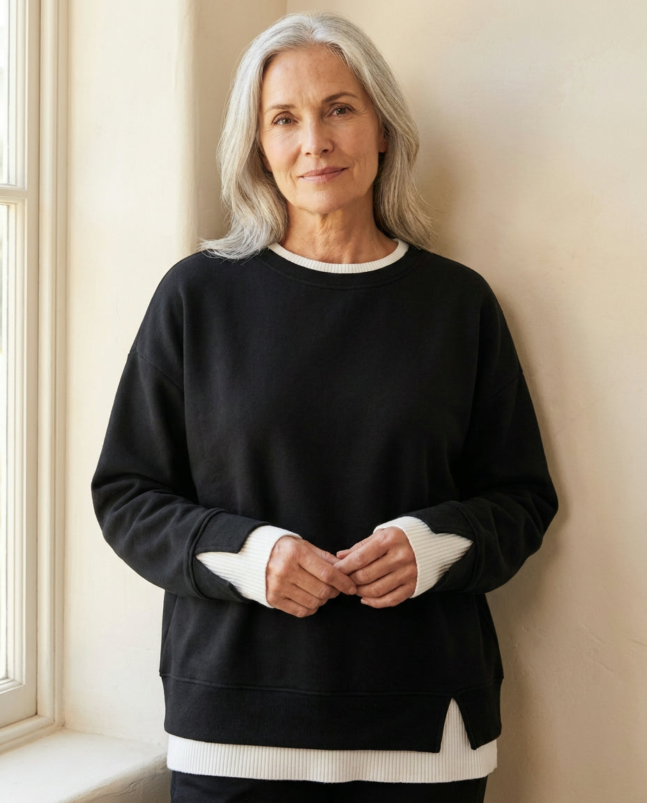 Woman wearing the Bruma layered sweatshirt against a cream wall