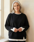 Woman wearing the Bruma layered sweatshirt against a cream wall