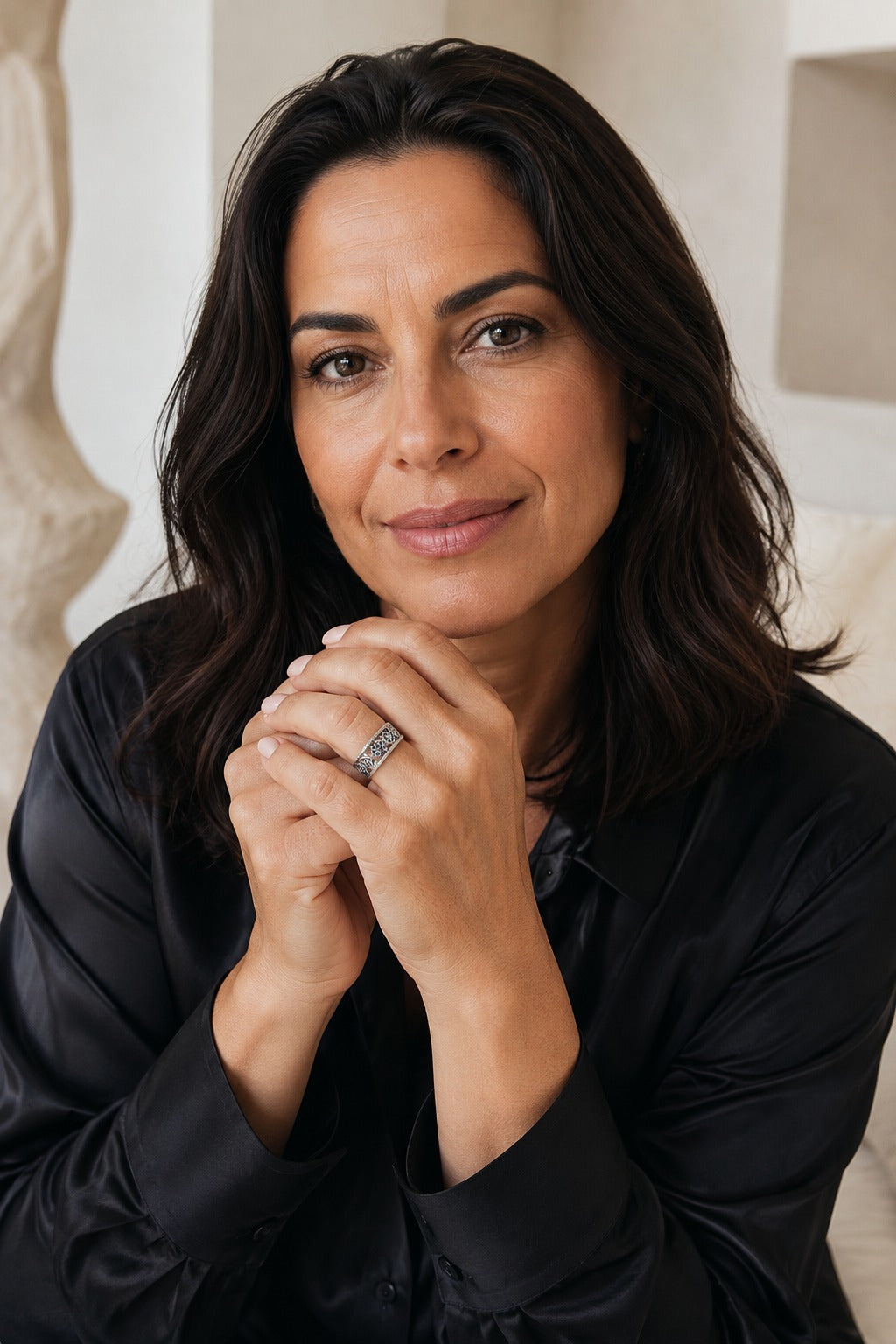 Woman in a black silk shirt with hands clasped wearing the Cetara Evil Eye Ring