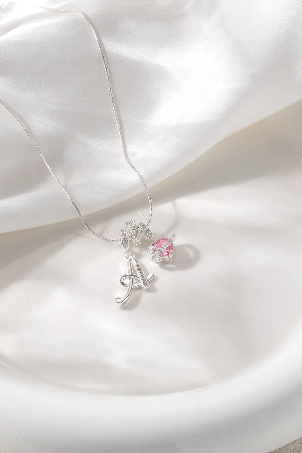 Cifra initial necklace resting on cream satin