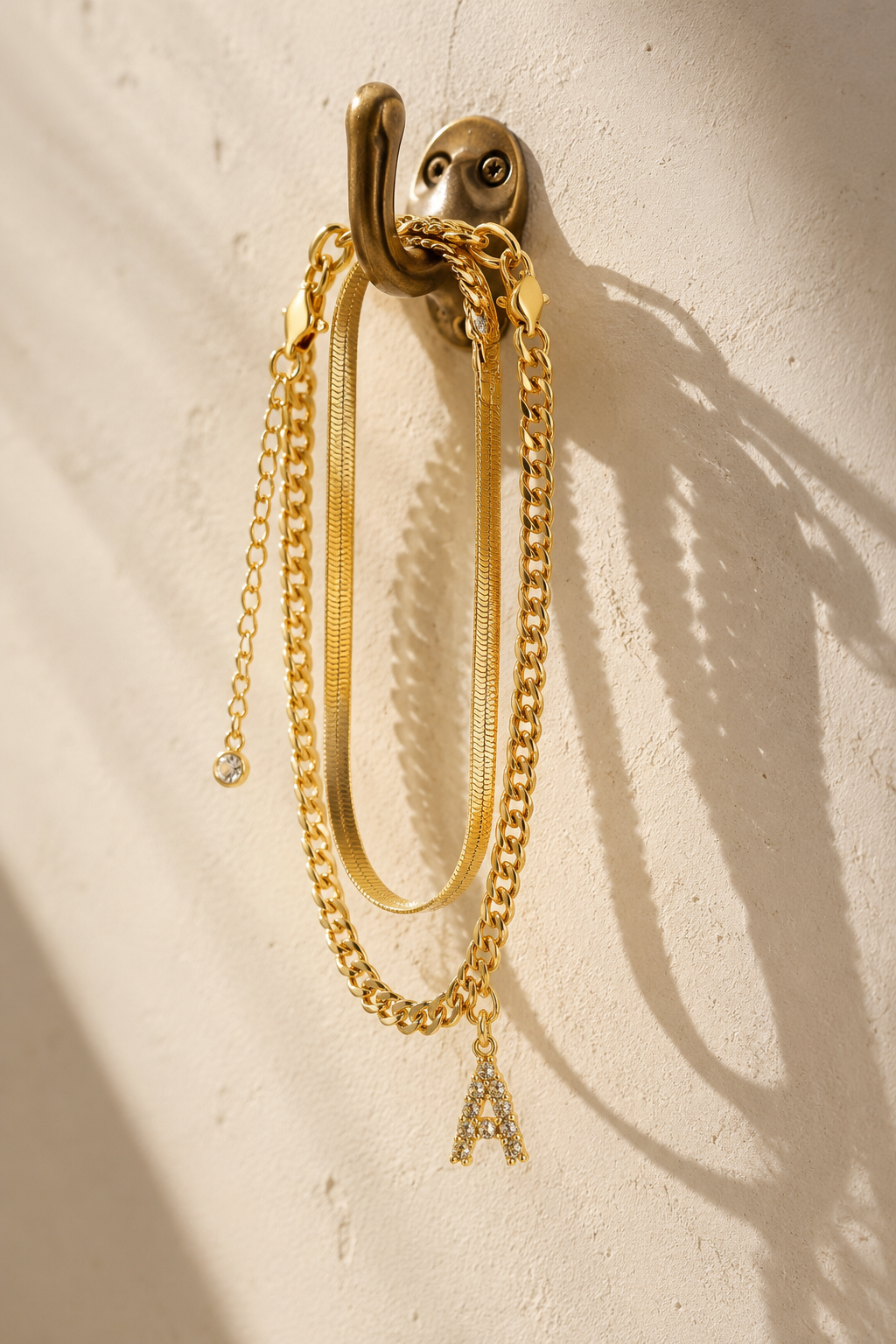 Marea anklet set hanging from a brass hook casting shadows