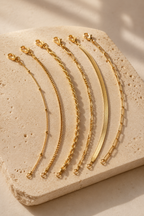 Sei six dainty gold chain bracelets on travertine
