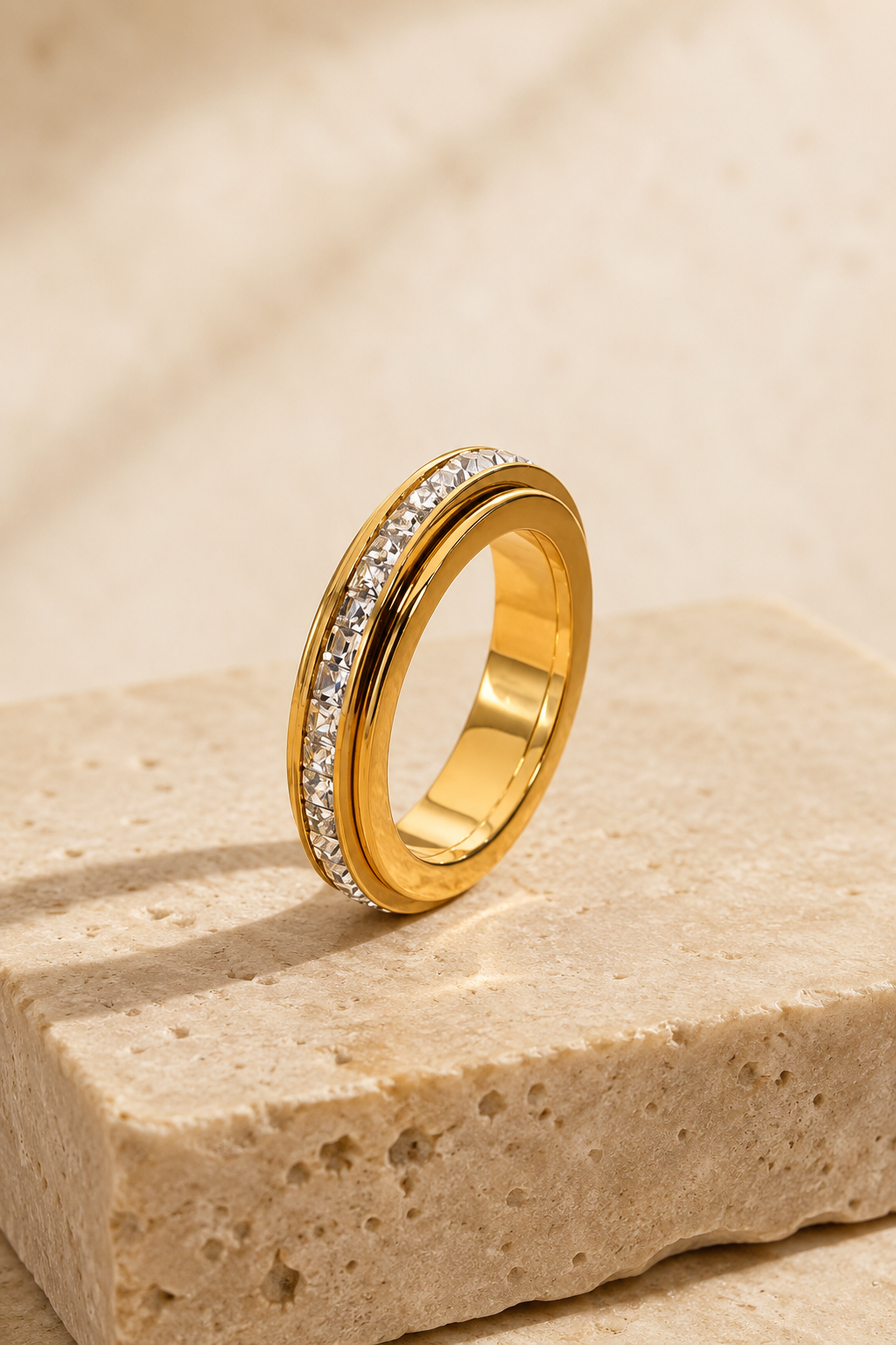 Gold Calma spinner ring on travertine stone