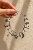 Incanto charm bracelet held between fingertips against a plaster wall