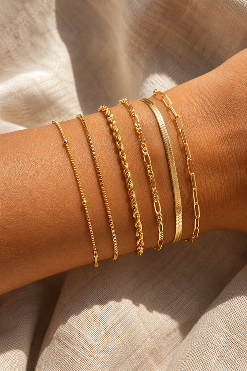 All six dainty gold chains stacked on a wrist