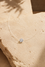 Goccia floating crystal necklace on warm travertine stone