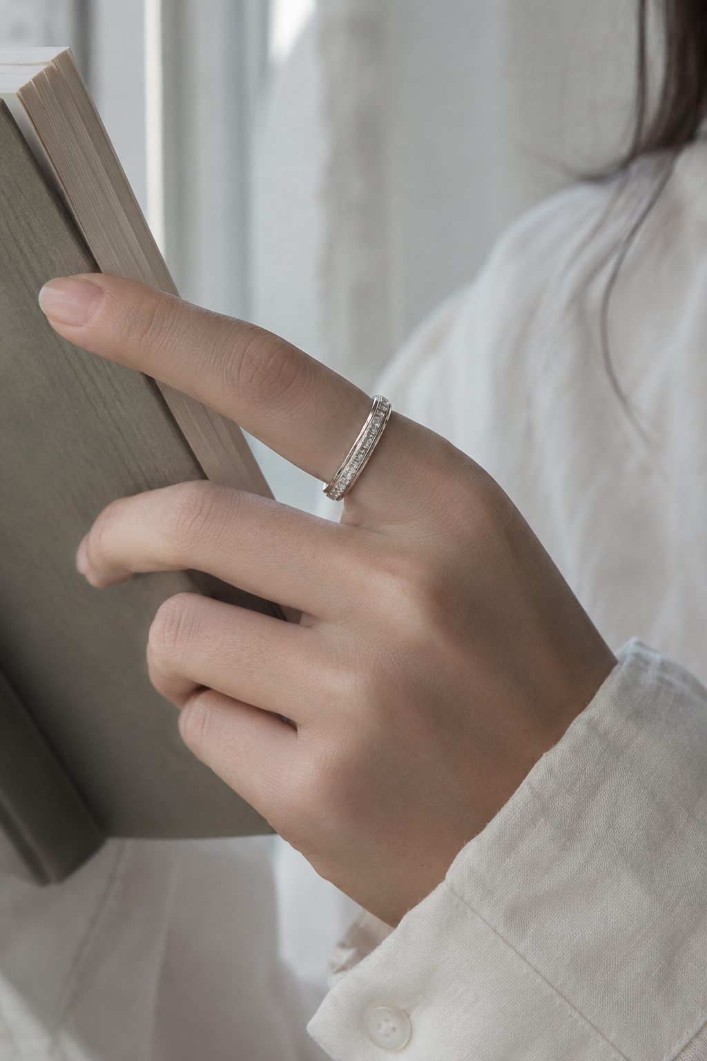 Silver Calma spinner ring worn while reading