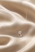 Goccia necklace resting on ivory silk