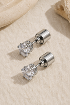 Lucciola studs unlit on cream linen, showing the plain clear crystal and the cylindrical battery backs
