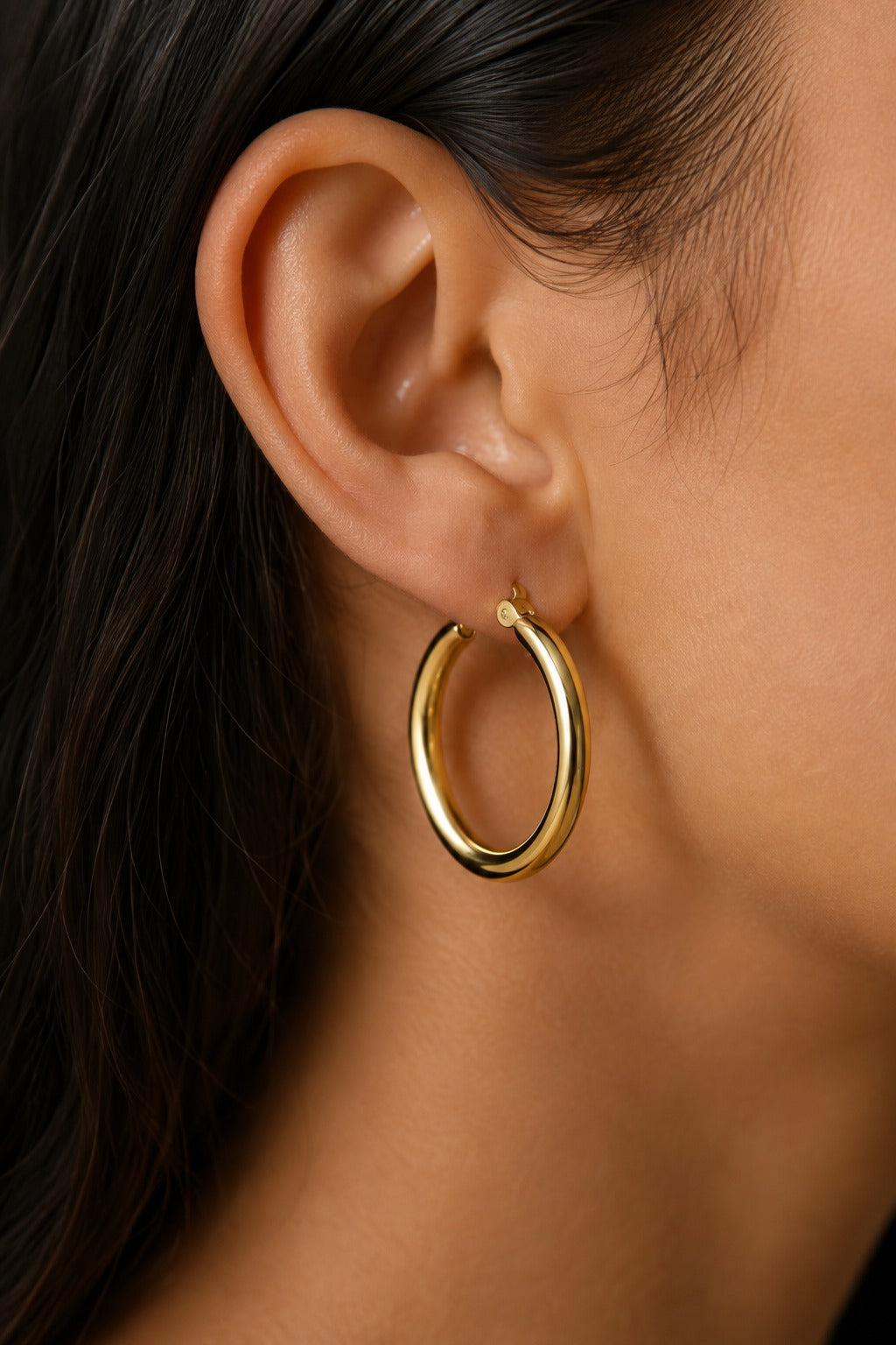 Close-up of an Ischia chunky gold hoop on the ear