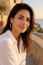 Woman wearing Ischia chunky gold hoops in golden-hour light