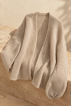 Nuvola oversized cardigan draped on warm travertine stone