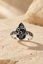 Ombra obsidian flower ring on warm travertine stone