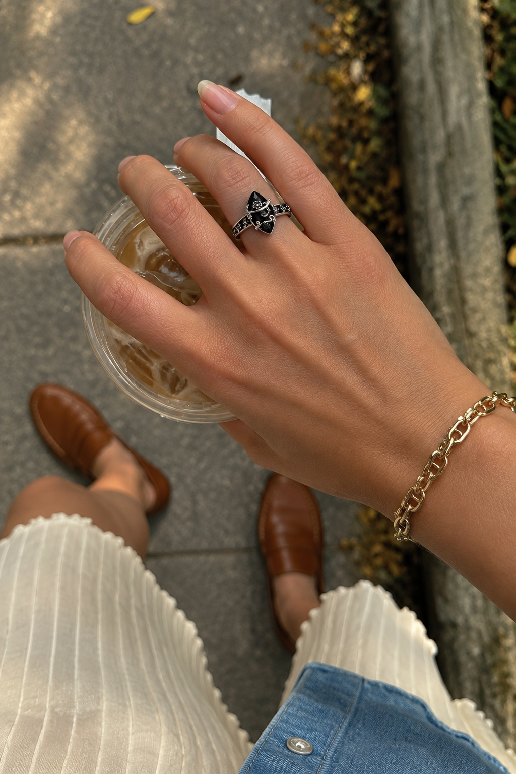 Hand holding an iced coffee wearing the Ombra obsidian ring
